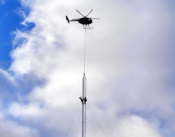 Ilmassa oleva helikopteri nostaa tuulimittausmastoa paikoilleen. 