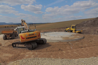 Baugeräte bei der Fundamentverfüllung Bagger, Walze und andere Baufahrzeuge verfüllen das Fundament der WKA