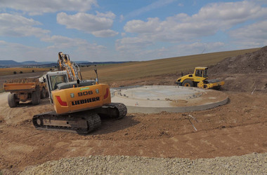 Bagger, Walze und andere Baufahrzeuge verfüllen das Fundament der WKA