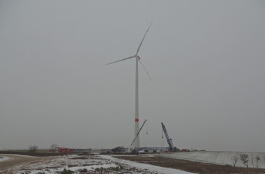 Auf einem winterlichen Feld steht die fertige Windenergieanlage vom Typ Nordex N 117
