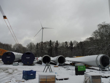 Zwei Turmkomponenten und die drei Rotorblätter für eine Windenergieanlage lagern am Homberg