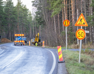 Liikennemerkkejä metsässä kulkevalla maantiellä.