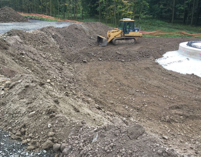 Mit einem Radlader wird die Baugrube rund um ein WEA-Fundament verfüllt