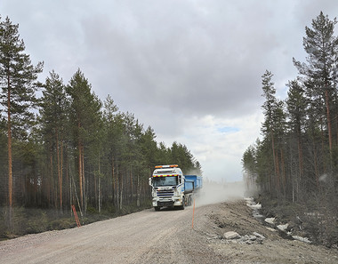 Rekka-auto ajaa maantiellä, ympärillä on metsää.