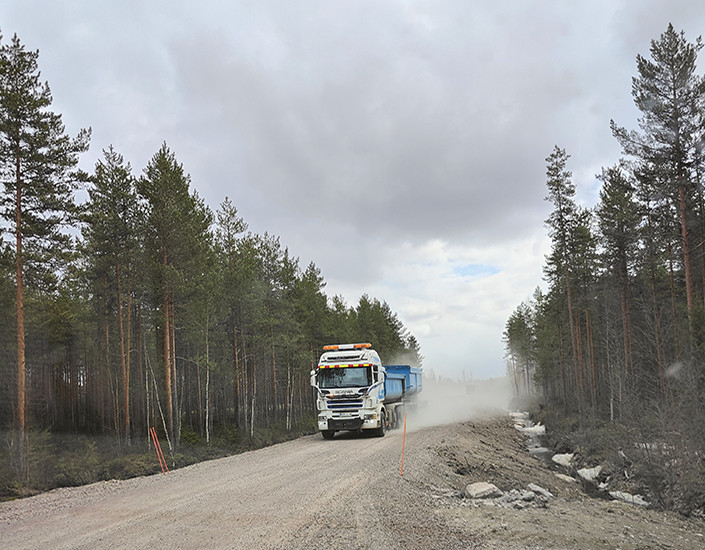 Rekka-auto ajaa maantiellä, ympärillä on metsää.