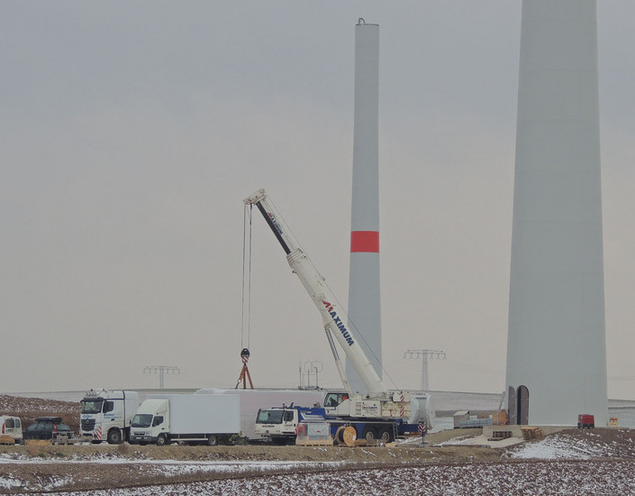 Ein Kran entlädt das Maschinenhaus direkt neben dem Betonturm