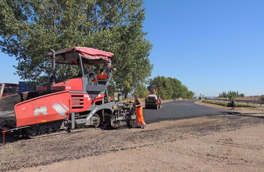 Einbau von Asphalt an der Anbindung zur Landesstraße Arbeiter stellen mit Hilfe von Baumaschinen ein asphaltiertes Wegstück her