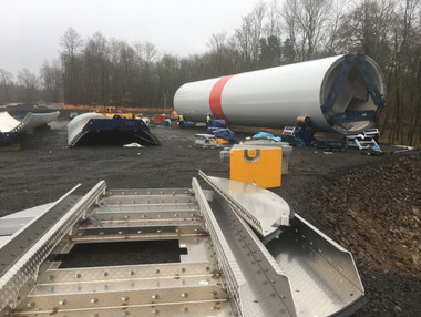 Auf der Baustelle lagern WEA-Komponenten, u.a. ein Turmsegment