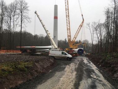 Groß- und Hilfskran positionieren ein WEA Rotorblatt auf der Baustelle